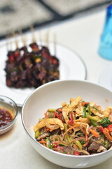 Christmas and New Year's dishes, consisting of meat satay with fried vermicelli and vegetables