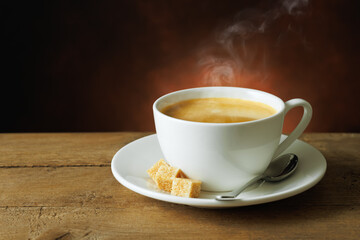 hot coffee with crema in cup and brown sugar cubes on saucer on wooden table