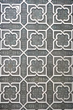 Closeup of vertical antique wall panel with traditional Islamic interlocking grid over intricate black design