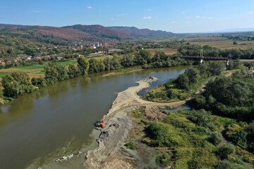 Aerial view of illegal exploitation of river sand and gravel with excavator on river bank
