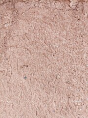 Close-up detail of adobe mud wall construction background pattern with small pebbles and short pieces of straw embedded in the surface