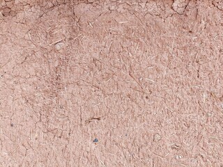 Dry adobe clay wall with bits of straw abstract monochromatic horizontal background texture