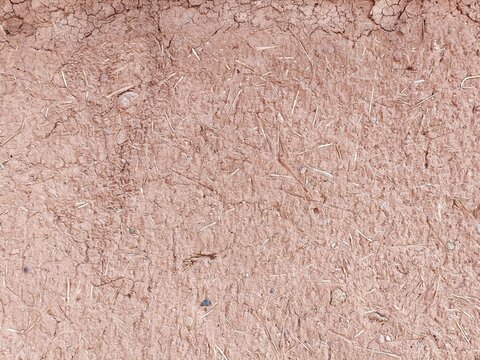 Dry adobe clay wall with bits of straw abstract monochromatic horizontal background texture