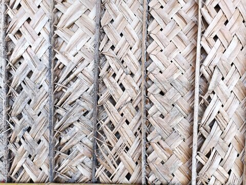 Multi-panel wall made from woven palm fronds with repeating crisscross sections