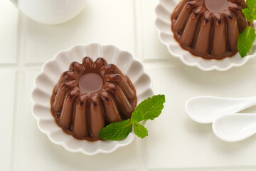 Chocolate pudding with mint leaf, served on a small white plate
