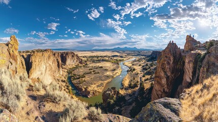 Obraz premium The panorama showcases the dramatic cliffs and vibrant landscape of Smith Rock State Park, featuring the Crooked River meandering through lush terrain under a brilliant sky.