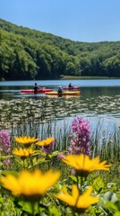 Bright yellow and pink wildflowers frame the peaceful Round Lake where kayakers glide across the calm water on a beautiful sunny day, surrounded by lush green hills.