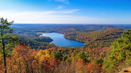Obraz premium The landscape reveals a breathtaking view of Oak Mountain State Park, with colorful autumn leaves framing a tranquil lake reflecting the bright blue sky.