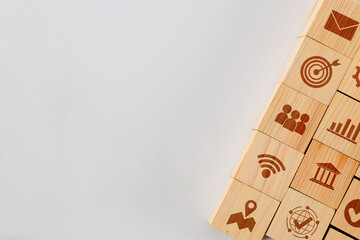 A stack of wooden blocks with various icons on them. The icons include a person, a building, a bank, a map, a globe, a house, a car, a cell phone, a Wi-Fi symbol, and an arrow