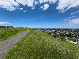 Auckland, New Zealand. Wide angle view of walking path around the crater of Te Kōpuke Mt St John, an extinct volcanic cone. Leafy suburbs Epsom and Remuera in distance.