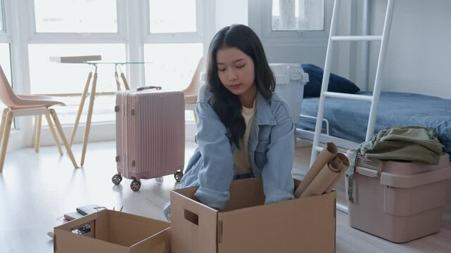 young woman is unpacking her belongings to move into her dorm in preparation for university
