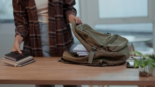 college woman putting notebook on backpack