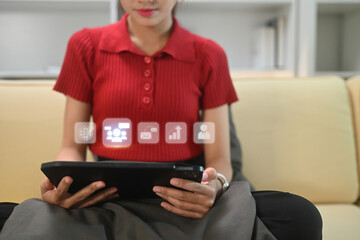 Young woman using digital tablet with glowing virtual icons for networking and data analytics displayed