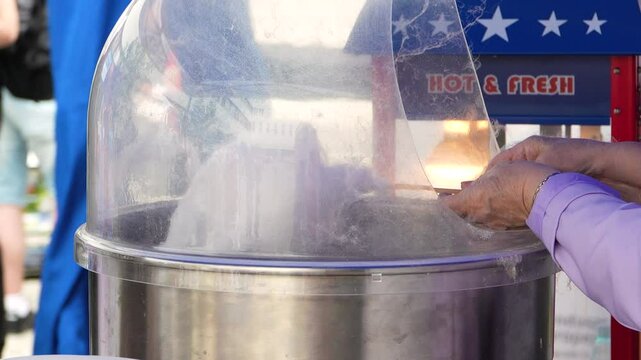 Old woman preparing cotton candy at the fair in slow motion