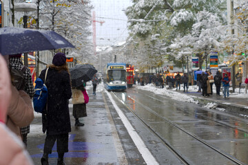 Cityscape at famous Bahnhofstrasse shopping mile with tram station and pedestrians on a snowy autumn afternoon. Photo taken November 22nd, 2024, Zurich, Switzerland.