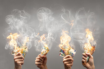 Burning Euro banknotes held by multiple hands