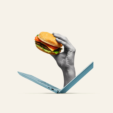 Naklejki A hand holding a burger emerges from a laptop.