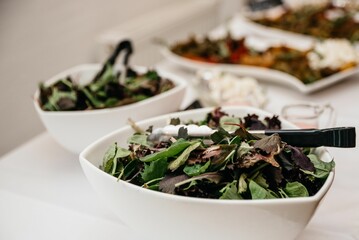 Fresh mixed greens in white bowls ready for serving.