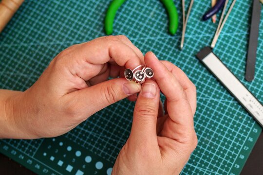 Jeweler skillfully crafting beautiful and unique silver rings with intricate designs and styles.