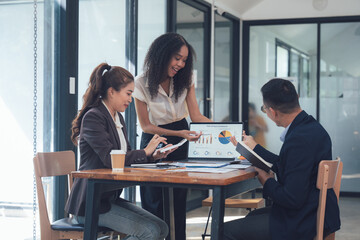 Teamwork Makes the Dream Work: A diverse team of business professionals collaborates around a laptop, reviewing data and charts during a productive meeting.  The image radiates a sense of teamwork.