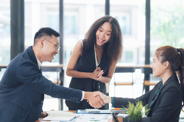 Successful Business Deal: A handshake seals a deal between diverse business professionals in a modern office setting.  The excitement and mutual respect are palpable. 
