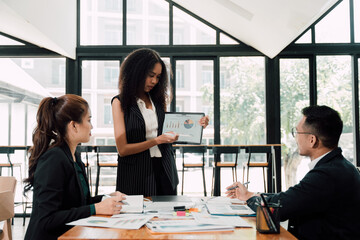 Business Presentation:  A diverse team of professionals engage in a lively discussion, analyzing data and sharing insights. The scene exudes a sense of collaboration, focus, and strategic planning.