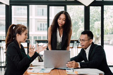 Collaborative Strategy Session: A team of diverse business professionals huddle around a laptop, engaging in a lively and focused discussion.  The image radiates energy.