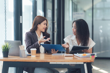 Businesswomen Collaborating: Two diverse professionals engaged in a dynamic discussion, showcasing their collaborative spirit and shared focus on achieving a common goal.