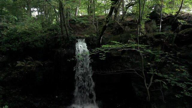 Pull-back drone footage of the Lumsdale Waterfall n Lumsdale Valley in Matlock, Derbyshire, England