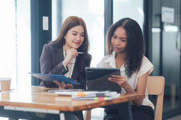 Collaborative Brainstorming: Two diverse businesswomen, engrossed in a productive discussion,...