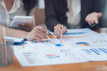 Strategic Collaboration: Close-up shot of two business professionals deeply engaged in analyzing financial charts and graphs, showcasing teamwork and meticulous planning.