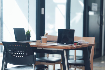 Modern Co-working Space: Two laptops rest on a sleek wooden table, ready for collaboration in a bright and airy modern workspace. The scene evokes a sense of productivity and innovation. 