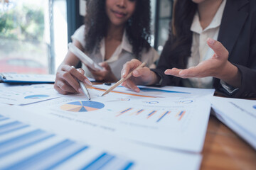 Businesswomen Analyzing Data: Two businesswomen collaborate on financial analysis, meticulously...