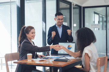 Obraz premium Successful Business Deal: A diverse team celebrates a successful business deal with a handshake, signifying trust, collaboration, and mutual success. The atmosphere is one of joy and accomplishment. 