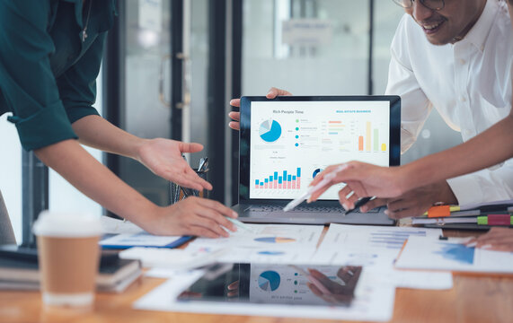 Business Data Analysis: Collaboration and Insight: A team of colleagues huddle around a laptop, analyzing data charts and graphs on the screen.