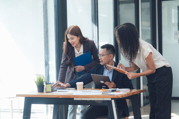 Collaborative Business Meeting: A diverse team of professionals collaborates around a table, engaging in a productive meeting using laptops, tablets, and documents.