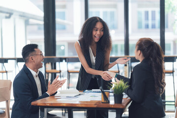 Successful Business Deal: A diverse team of business professionals celebrates a successful deal, shaking hands and expressing their excitement.