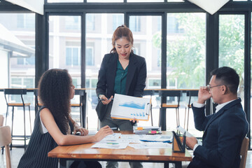 Business Meeting Presentation: A focused businesswoman confidently presents a financial chart during a productive meeting with her colleagues.  The image evokes professionalism and collaboration.