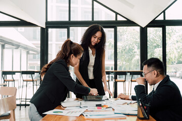Business Professionals Collaborating: A diverse team of three professionals engaged in a collaborative discussion around a conference table, showcasing their commitment to teamwork and shared goals.
