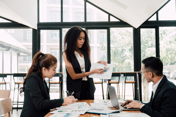 Business Meeting: A diverse team of professionals gathers around a table, analyzing data and collaborating on a project.
