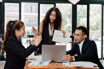 Business Presentation: A diverse team of professionals engaged in an animated discussion. The woman in the center, holding a chart, appears to be making a compelling point to her colleagues.
