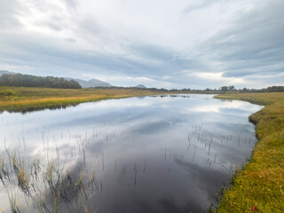 Calm crystal clear water reflecting mountains in northern norway under a cloudy sky