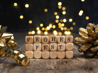Wooden blocks with Frohes fest against blurred Christmas lights, German Merry Christmas