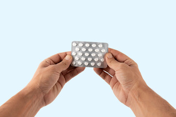 Male hands holding a medicine blister isolated on cyan background