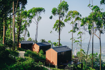 Small lodging houses are located in a lush green forest, with a panoramic view.
