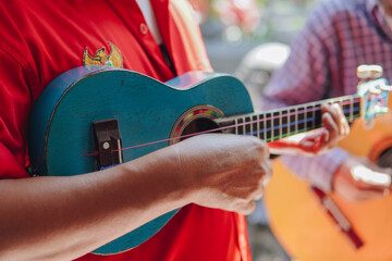 Busker group of men playing ukulele music instrument to entertain people.