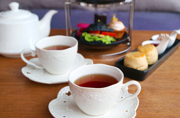 Closeup of Two Cups of Hot Tea with Blurry Afternoon Tea Pastries in the Backdrop