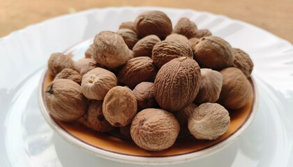 Bunch, heap or pile of organic and fresh cracked dry brown myristica or nutmeg seeds inside a bowl. Ayurvedic medicine spice ingredient. Beautiful 4k extreme close up side view.