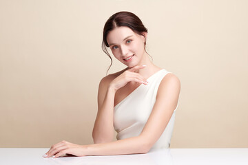 Naklejka premium Beautiful young woman with clean fresh skin on beige background, Face care, Facial treatment, Cosmetology, beauty and spa, women portrait.