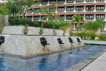 Water fountain pool in the hotel outdoor park with the hotel building in the background.